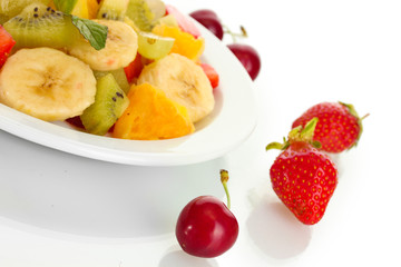 Fresh fruits salad on plate and berries isolated on white