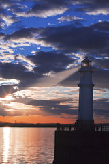 Lighthouse at sunset with light beam