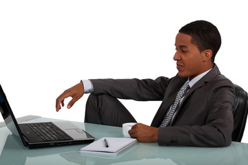 Young businessman sat at laptop with coffee in hand