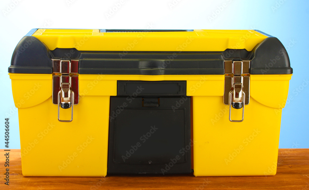 Wall mural yellow tool box on blue background close-up