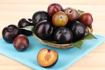 Rip plums on basket on wooden table