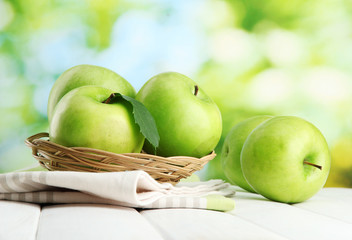 Ripe green apples with leaves in basket,