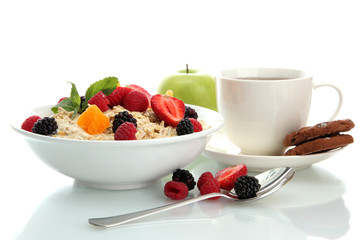 tasty oatmeal with berries and cup of tea, isolated on white
