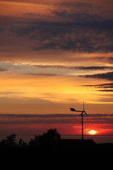 Small private windtubine stands in enjoyable sunset