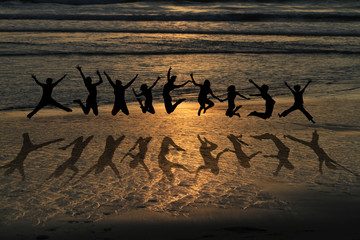 friends jumping on beach in sunset