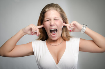 Pretty girl screaming with fingers in ears