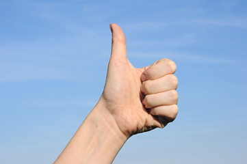Thumbs up against a blue sky