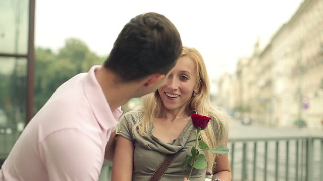 Young man giving rose to his girlfriend in the city