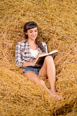 Naklejka na ściany i meble Girl reading book on haystack