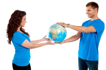 Fototapeta premium Causal young couple holding globe together