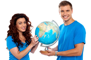 Joyful couple holding globe and smiling at camera
