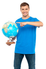 Casual cool guy pointing at rotating globe