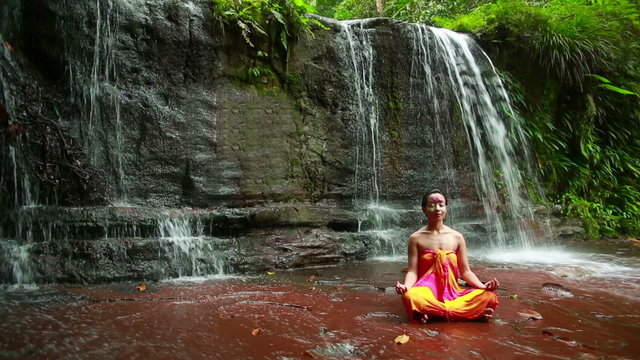 Meditating with Facial Painting in borneo rainforest waterfall