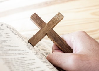 man holding the cross with bible