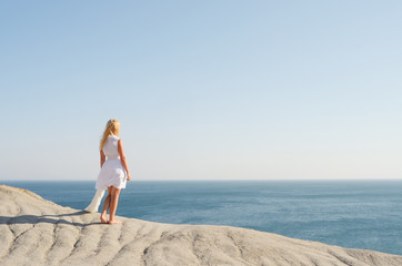 Fototapeta na wymiar Girl in white dress looks on the sea