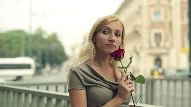 Young beautiful sad woman with rose in the city, steadicam shot