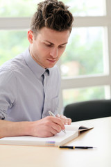 Young adult man writing note