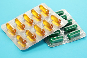 Capsules packed in blisters, on blue background