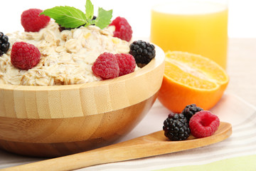 tasty oatmeal with berries and glass of juice, on wooden table