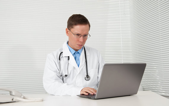 male doctor works on his laptop computer