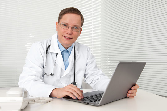 doctor in white coat with laptop computer