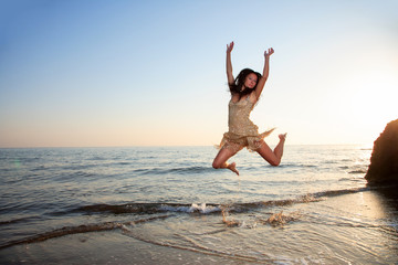 Fototapeta na wymiar Young woman jumping on a beach