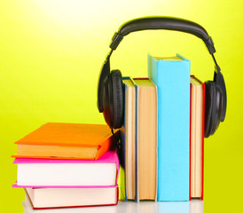 Headphones on books on green background