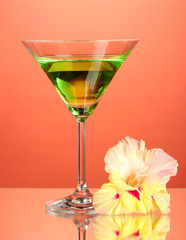 glass with cocktail and gladiolus bud on red background