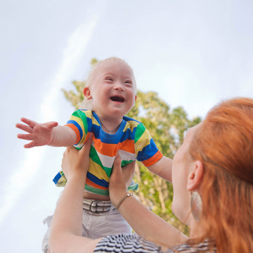 baby with Down syndrome is happy and flying up