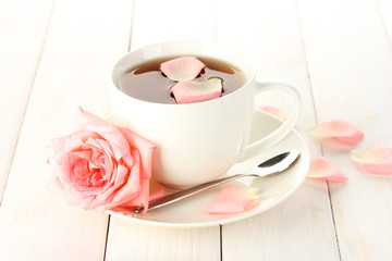 cup of tea with rose on white wooden table