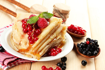 Delicious pancakes with berries, jam and honey on wooden table