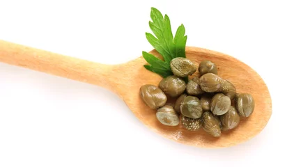 Poster green capers in wooden spoon on white background close-up © Africa Studio
