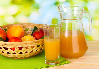Ripe peaches and juice on wooden table on natural background