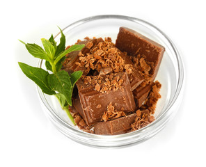 Pieces of chocolate and mint in the bowl isolated on white