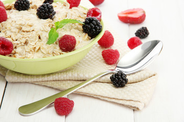 tasty oatmeal with berries, on white wooden table