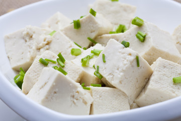 Tofu and sliced scallion in white bowl.