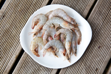 Uncooked tiger prawns on a white plate.
