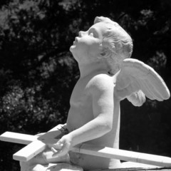 little angel looking up and holding cross, headstone sculpture