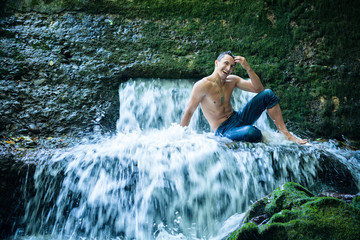 Happy young man having fun and relax under waterfall.