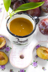 Plum juice and fresh fruits with leaves