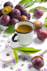 Plum juice and fresh fruits with leaves
