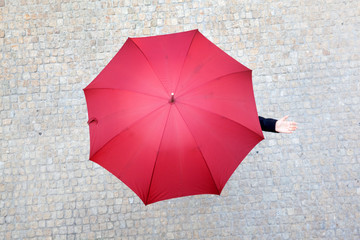 Business woman hidden under umbrella and checking if it's rainin