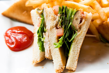 Sandwich with chicken, cheese and golden French fries potatoes