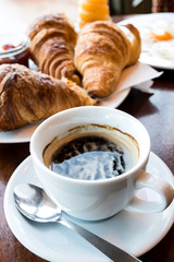 Breakfast with coffee and croissants in a basket on table