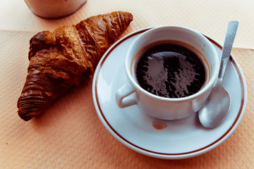 Breakfast with coffee and croissants in a basket on table
