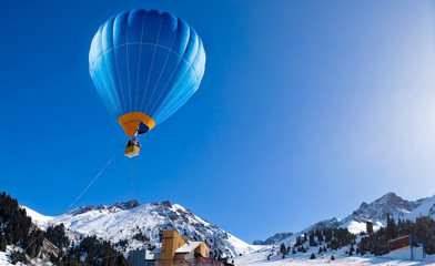 Balloon flying above mountain range at clear blue sky