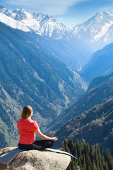 Naklejka na ściany i meble Young woman meditating on top of the mountain