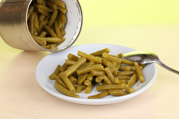 Open tin can and plate with french bean and spoon