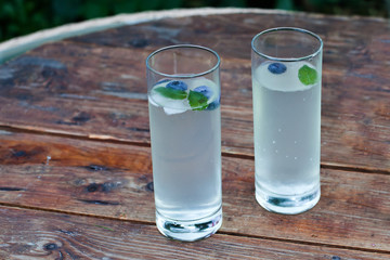 Two glasses of home made iced cold lemonade on wooden table