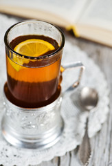 Tea with lemon in the glass-holder and book
